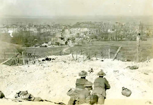 Soldiers laying in the trenches looking across a field into a city centre